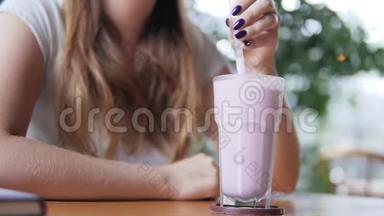年轻漂亮的欧洲女孩在炎热的夏日在咖啡馆里喝着冰镇牛奶鸡尾酒和蓝莓。 妇女饮酒